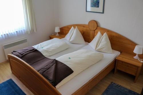 a large wooden bed with white pillows on it at Haus Alpina in Sonnenalpe Nassfeld