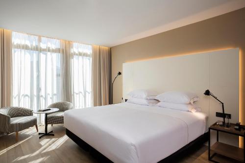 a bedroom with a large white bed and a chair at Casa Elliot Hotel in Barcelona