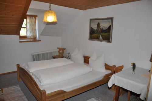 a bedroom with a white bed and a table at Gasthof Neuwirt in Ellbögen