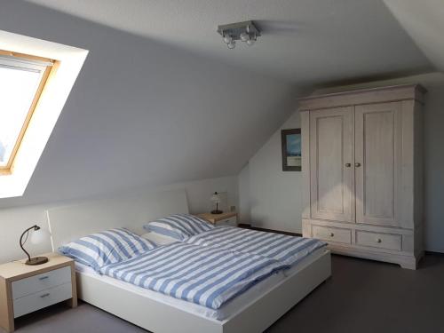 - une chambre blanche avec un lit et une armoire dans l'établissement Darßer Weg 32a "Kormoran" Wohnung 16, à Zingst