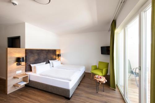 a bedroom with a white bed and a green chair at Schnitzers Dahoam - Hundefreundlich in Bad Wiessee