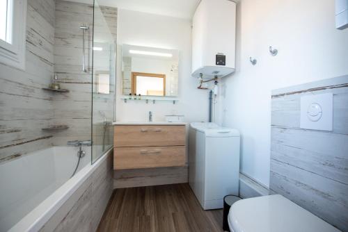 uma casa de banho com uma banheira, um WC e um lavatório. em Charmant appartement avec vue imprenable sur la mer em Les Sables-dʼOlonne