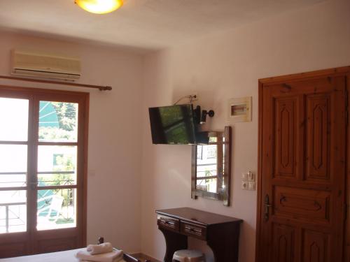 um quarto com uma televisão, uma janela e uma porta em SKIATHOS STUDIOS em Skiathos Town