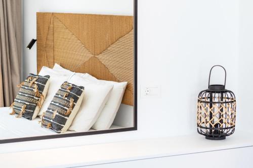 a mirror on a bed with pillows and a lamp at Alkithea luxury suites in Karpathos Town