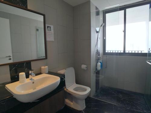 a bathroom with a sink and a toilet and a mirror at The Landmark by Comfy in George Town