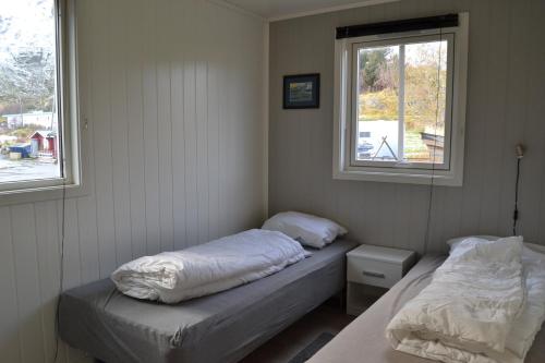 two beds in a room with two windows at Sjøstrand Rorbuer v Børge Iversen AS in Ballstad