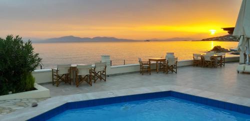 a pool with a table and chairs and a sunset at Irides in Souvala