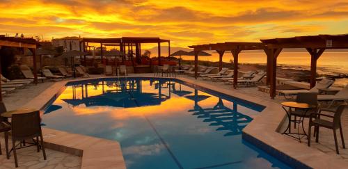 a pool on the beach with chairs and a sunset at Irides in Souvala
