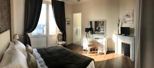 een slaapkamer met een bed, een bureau en een spiegel bij La Maison de Louisette in Le Faouët