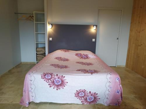 ein Bett mit einer rosa Decke mit Blumen drauf in der Unterkunft Limone Vallée in Montrigaud
