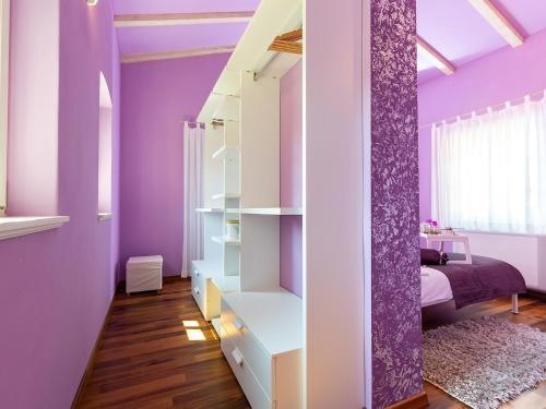 a purple bedroom with a bed and a purple wall at Villa Salvea with heated pool in Montižana