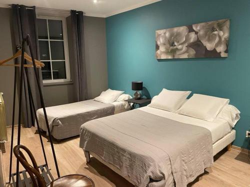 ein Schlafzimmer mit 2 Betten und einer blauen Wand in der Unterkunft Hôtel Le Globe in Marsanne