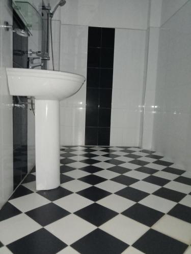 a bathroom with a sink and a black and white checkered floor at Viraj's Garden in Tangalle