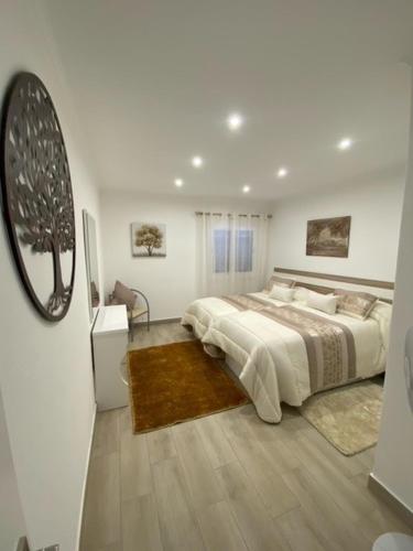 a white bedroom with a bed and a mirror at Monte Gordo apartment in Monte Gordo
