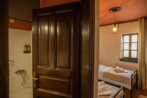 a door to a bathroom with a bed and a tub at Charis Guesthouse in Makrinítsa