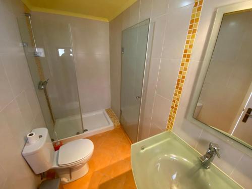 een badkamer met een toilet, een douche en een wastafel bij O Cantinho do Sol in Lourinhã