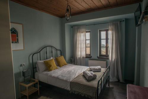 a bedroom with a bed with yellow pillows and a window at Charis Guesthouse in Makrinítsa