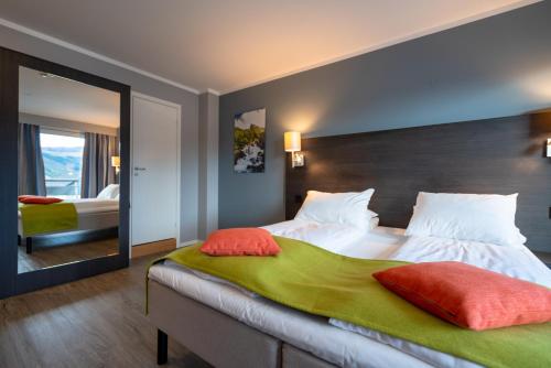 - une chambre avec un grand lit et un grand miroir dans l'établissement Thon Partner Hotel Måløy, à Måløy
