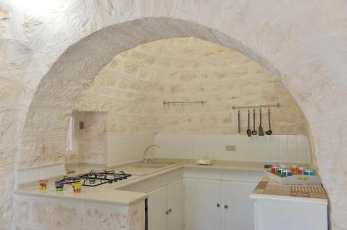 een witte keuken met een spoelbak en een fornuis bij I Trulli del Tempo in Martina Franca
