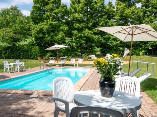 a table with an umbrella next to a swimming pool at Apartment Cascina Virginia-3 by Interhome in Vigliano d'Asti
