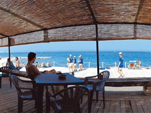 a man sitting at a table on the beach at Holiday Home Camping La Masseria-2 by Interhome in Il Monte