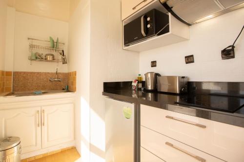 a kitchen with white cabinets and a black counter top at Junior Suite Balima I B43 in Rabat