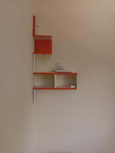 a shelf on a white wall with a red box at Kër Adja in Ziguinchor