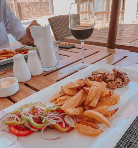 a plate of food on a table with a glass of wine at Paje Blu Boutique Hotel in Paje