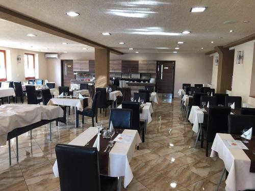 a dining room with white tables and black chairs at Royal Hotel in Cserkeszőlő
