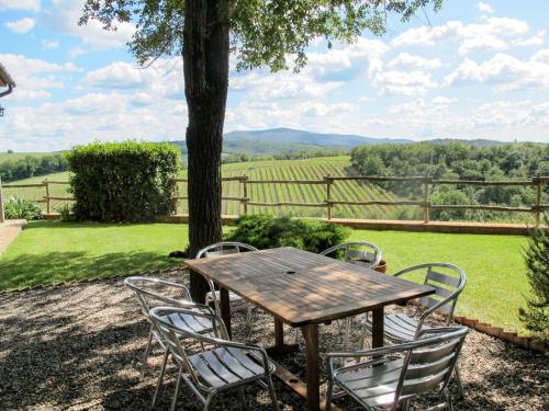 una mesa y sillas de madera con vistas a un campo en Holiday Home Cignanbianco - Alba by Interhome, en Castellina in Chianti