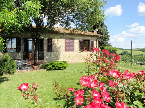 a stone house with red flowers in front of it at Holiday Home Cignanbianco - Alba by Interhome in Castellina in Chianti