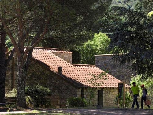 two people walking in front of a stone house at Apartment Les Vans-Cottage 3 pièces 6 personnes by Interhome in Chambonas