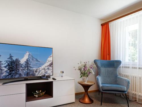 un salon avec une télévision et une chaise bleue dans l'établissement Apartment Hubertus-1 by Interhome, à Zermatt