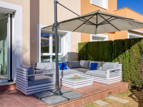 eine Terrasse mit einem Sofa und einem Sonnenschirm in der Unterkunft Holiday Home Malibu Beach by Interhome in Oliva