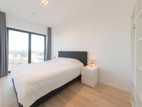 een witte slaapkamer met een bed en een raam bij Apartment Baelskaai 25 by Interhome in Oostende