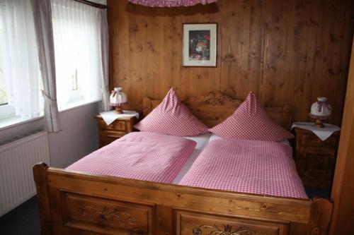 Schlafzimmer mit einem Holzbett mit rosa Bettwäsche und Kissen in der Unterkunft Stefans Gästezimmer in Kirchhatten