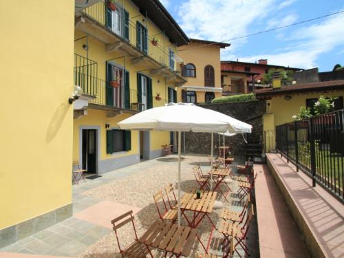 um grupo de mesas e cadeiras com guarda-sol em Apartment Giardino del Bosso-4 by Interhome em Germignaga