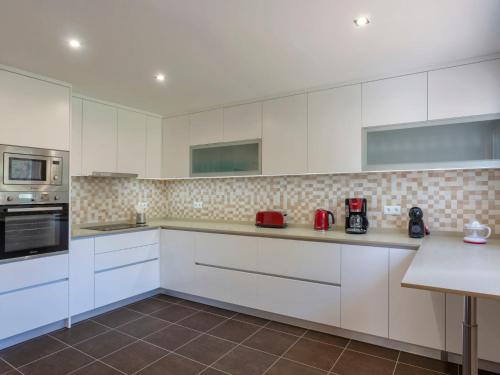 una cocina blanca con armarios y electrodomésticos blancos en Villa Be Grateful by Interhome, en Mexilhoeira Grande