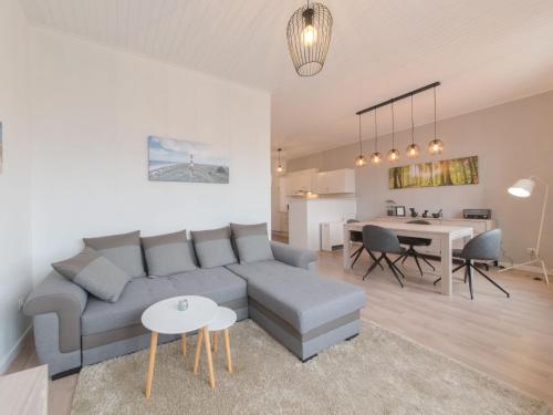ein Wohnzimmer und eine Küche mit einem Sofa und einem Tisch in der Unterkunft Apartment Carnac Station by Interhome in De Haan