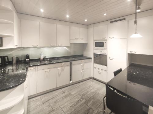 a kitchen with white cabinets and a black counter top at Apartment Perla by Interhome in Davos