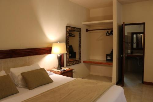 a bedroom with a bed with a mirror and a lamp at The Diving Lodge Downtown in Puerto Morelos