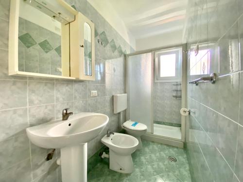Baño blanco con lavabo y aseo en Rialto, en Lignano Sabbiadoro
