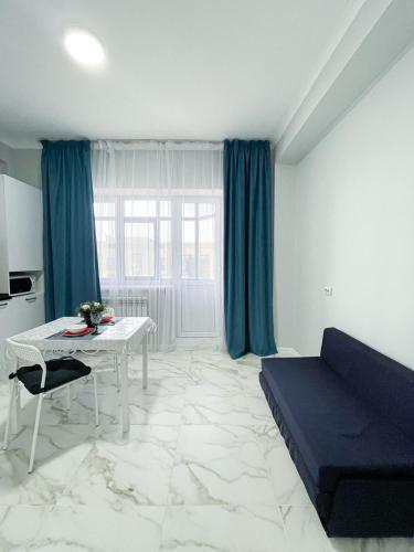 a living room with a table and a blue couch at ЖК Баспана in Atyraū