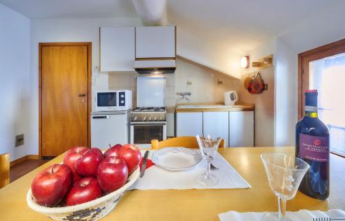 a table with a bowl of apples and a bottle of wine at Romantic house in Varenna