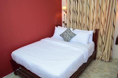 1 cama con sábanas blancas y almohadas en una habitación en Absor Royal Hotel, en Koforidua