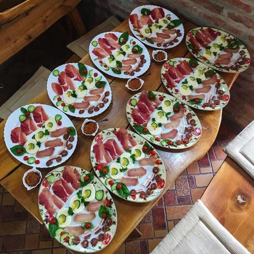 a wooden table with many plates of food on it at Podrum Miljević in Ledinci