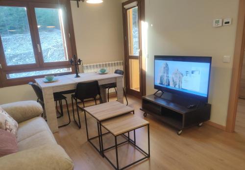 sala de estar con TV y mesa con sillas en Apartamento a estrenar en Villanúa, en Villanúa