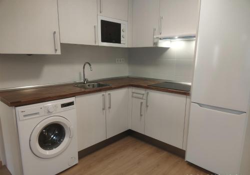 cocina con armarios blancos y lavadora en Apartamento a estrenar en Villanúa en Villanúa