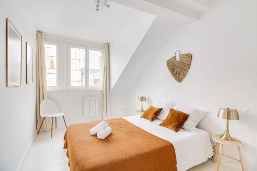 biała sypialnia z dużym łóżkiem z pomarańczowymi poduszkami w obiekcie NOCNOC - Le Magnifique w Lille