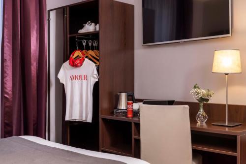 a hotel room with a bed and a shirt hanging on a closet at Hôtel L'Interlude in Paris